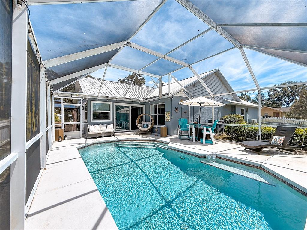 A screened-in swimming pool patio features a lounge area, dining set, and a chaise lounge — 1050 FAHNSTOCK STREET, EUSTIS, FL