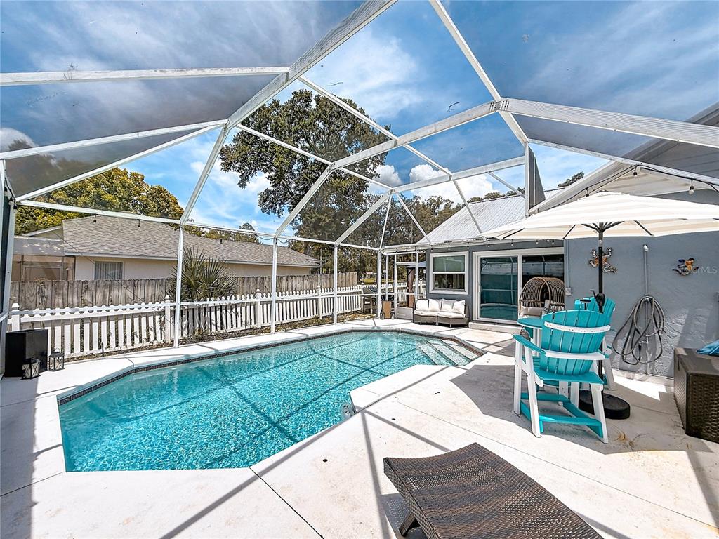 A screened-in patio features a swimming pool, outdoor furniture, and a white picket fence — 1050 FAHNSTOCK STREET, EUSTIS, FL