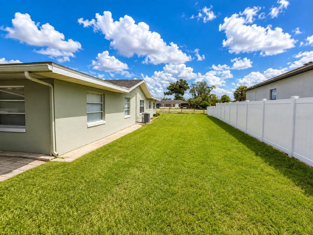 A backyard with a green lawn, a light-colored house exterior, and a white vinyl fence — 5039 OLD CHENEY HIGHWAY UNIT B, ORLANDO, FL