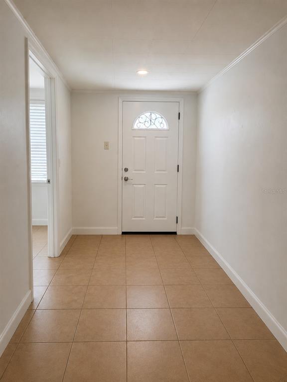 A bright entryway features white walls, tan tile flooring, and a white front door — 5039 OLD CHENEY HIGHWAY UNIT B, ORLANDO, FL