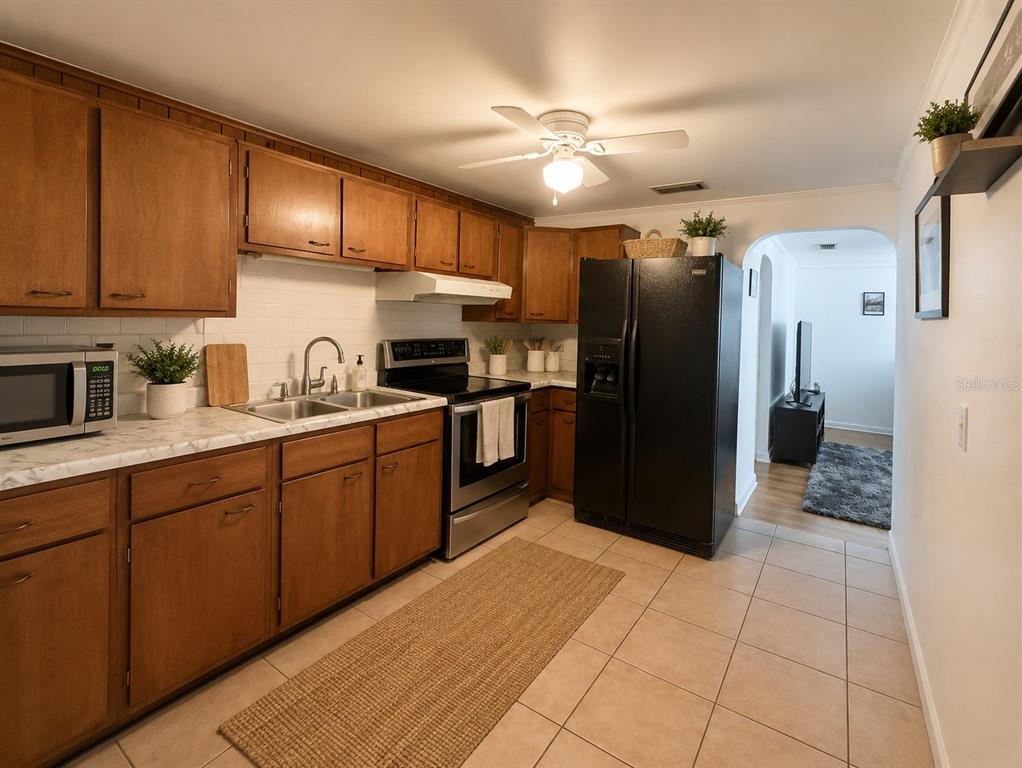 A kitchen features wood cabinets, a black refrigerator, stainless steel appliances, and tile flooring — 5039 OLD CHENEY HIGHWAY UNIT B, ORLANDO, FL