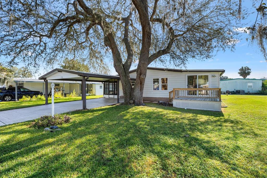 A single-story house with a carport and a wooden deck under a large oak tree — 732 ROYAL PALM AVENUE, THE VILLAGES, FL
