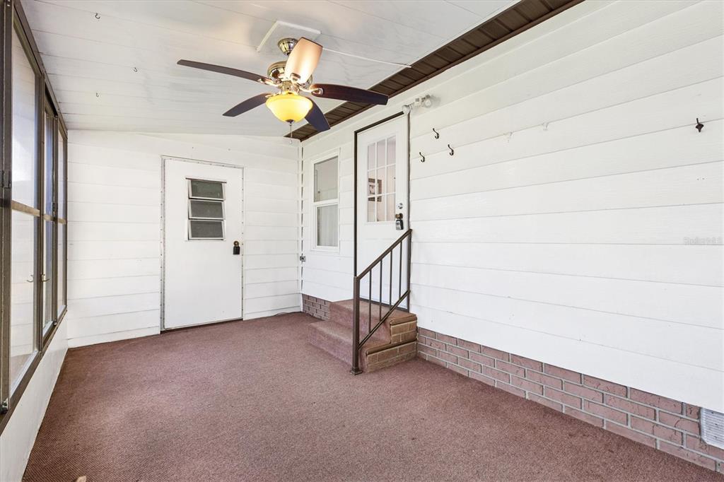 A covered porch features white horizontal siding, a ceiling fan, brown carpeting, and brick accents — 732 ROYAL PALM AVENUE, THE VILLAGES, FL
