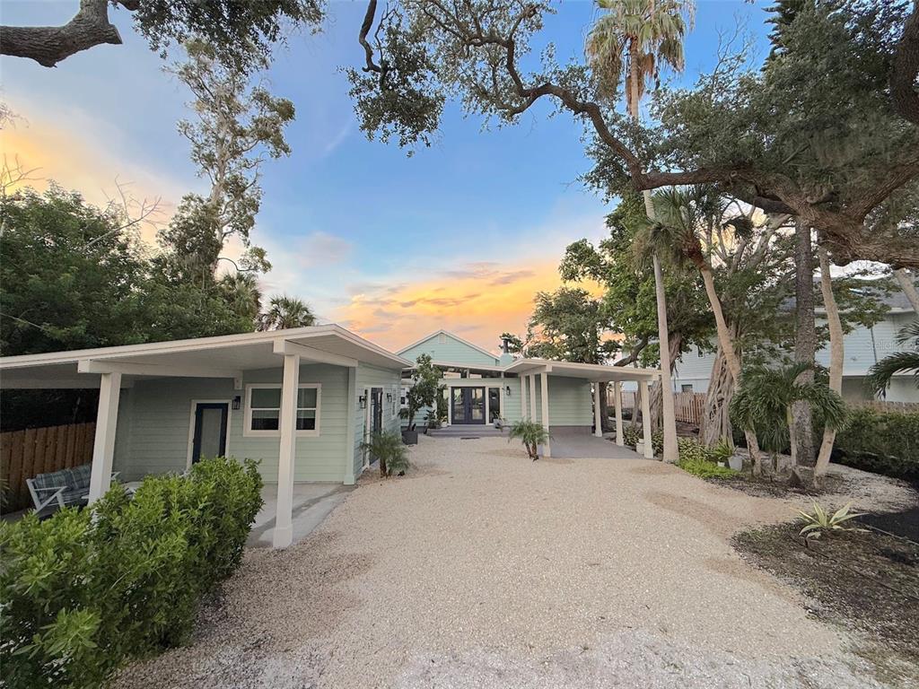 An aerial view shows a waterfront house with a gravel driveway and surrounding palm trees — 1275 PORT LANE, SARASOTA, FL