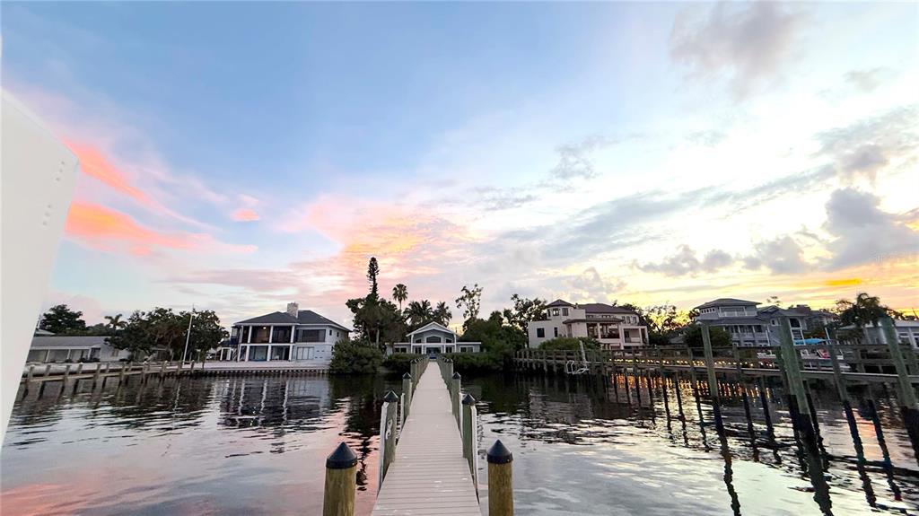 An exterior view of a light green house with a gravel driveway and covered porches — 1275 PORT LANE, SARASOTA, FL