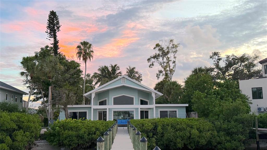 A long wooden dock with a boat lift extends into a canal toward waterfront houses — 1275 PORT LANE, SARASOTA, FL