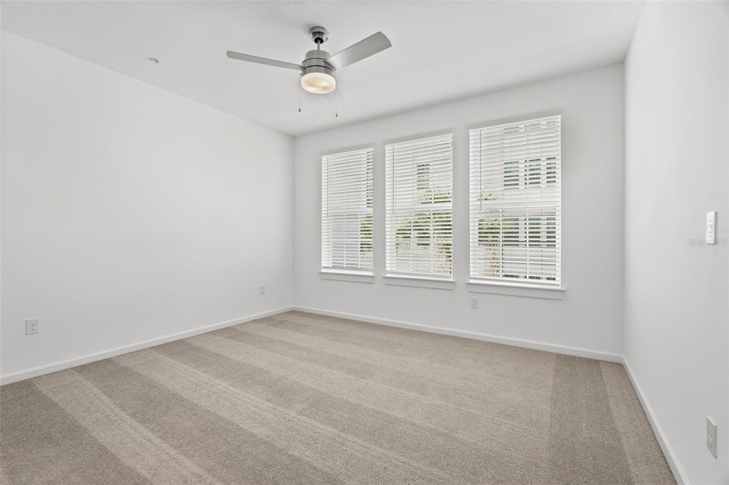 An empty bedroom with white walls, beige carpet, a ceiling fan, and three windows — 1700 RANCH ROAD UNIT B3-6315, NOKOMIS, FL