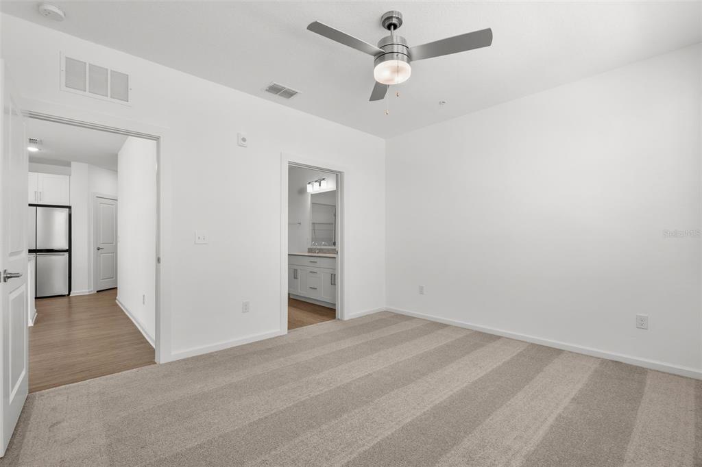 A bedroom with beige carpet, white walls, a ceiling fan, and doorways leading to other rooms — 1700 RANCH ROAD UNIT B3-6315, NOKOMIS, FL
