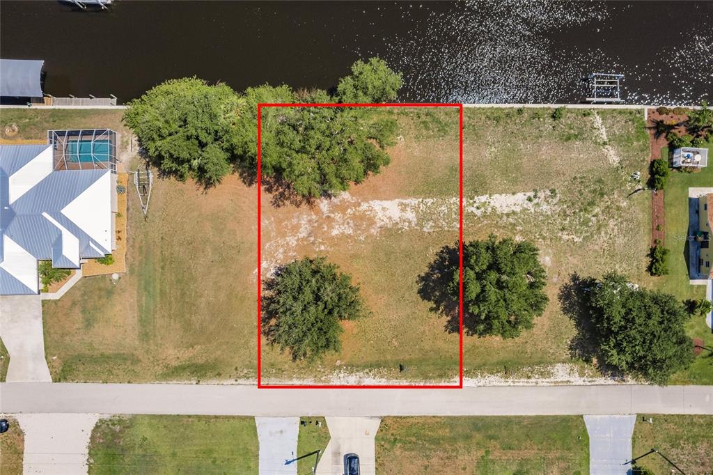 An aerial view shows a rectangular vacant waterfront lot outlined in red — 28451 SILVER PALM DRIVE, PUNTA GORDA, FL