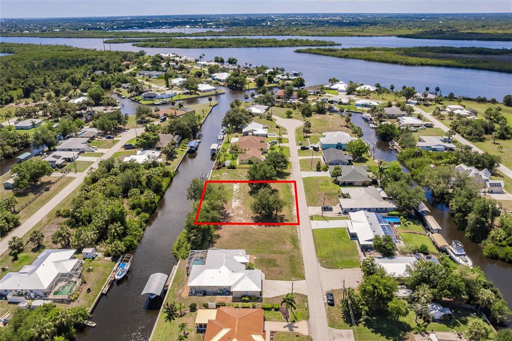 An aerial view shows a vacant, rectangular waterfront lot outlined in red between two houses — 28451 SILVER PALM DRIVE, PUNTA GORDA, FL