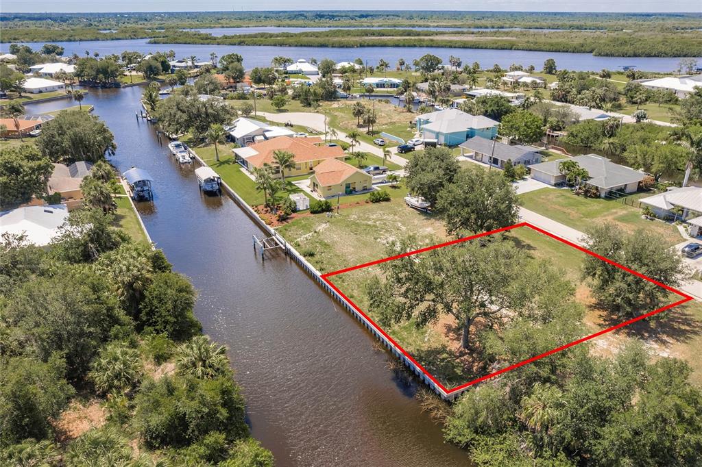 An aerial view shows a vacant waterfront lot outlined in red along a canal — 28451 SILVER PALM DRIVE, PUNTA GORDA, FL
