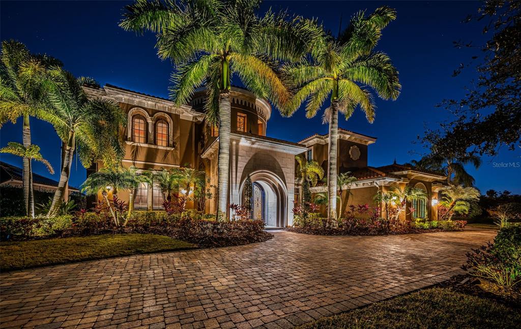 A two-story Mediterranean-style house with a paved driveway and palm trees at night — 9209 SILVERTHORN ROAD, SEMINOLE, FL