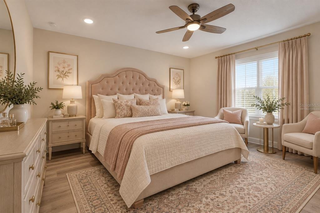 A bedroom features a large ornate bed, two armchairs, a ceiling fan, and light wood flooring — 10169 SPRING LAKE DRIVE, CLERMONT, FL
