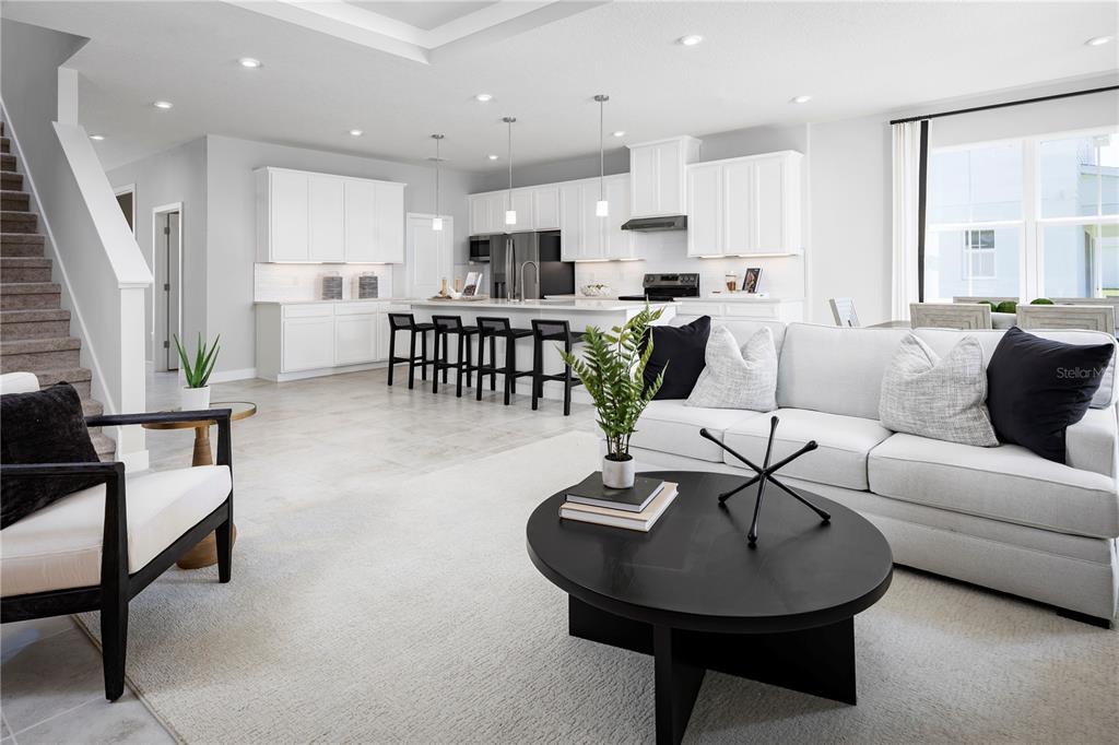 An open-concept living room and kitchen feature white cabinetry, a kitchen island, and neutral decor — 22145 PINE GROVE LOOP, LEESBURG, FL