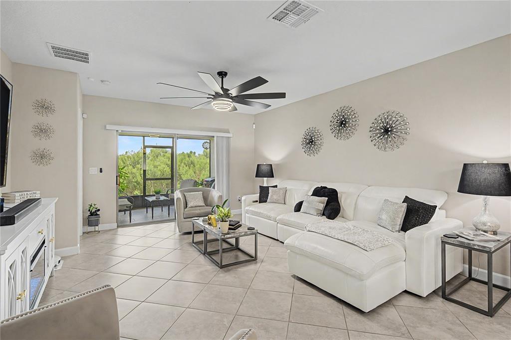 A living room features a white sectional sofa, tile flooring, a ceiling fan, and sliding doors — 10228 ECHO DOCK LOOP, SAN ANTONIO, FL