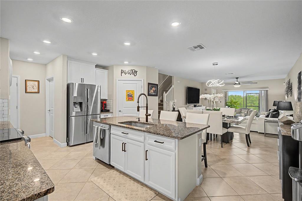 A kitchen with white cabinets, granite countertops, and a center island overlooks a dining area — 10228 ECHO DOCK LOOP, SAN ANTONIO, FL