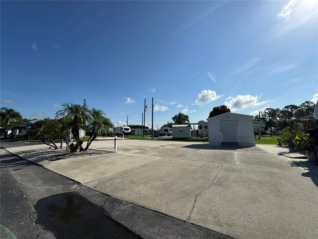 A paved lot features a small storage shed, palm trees, and several parked recreational vehicles — 1389 SHIPWRECK LANE, ST CLOUD, FL
