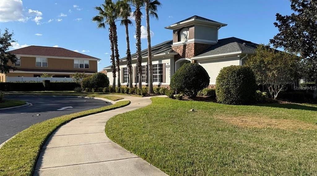 A grassy backyard features a black metal fence overlooking a lake under a blue sky — 4619 CABALERRO TRAIL, KISSIMMEE, FL