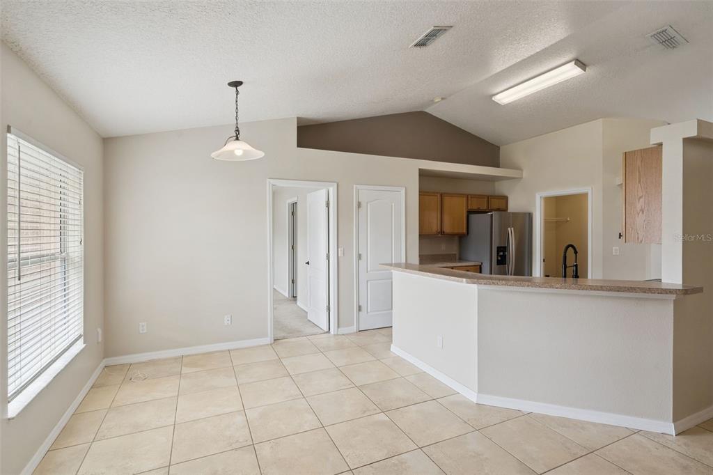 A dining area with tile flooring, a pendant light, and an open kitchen with breakfast bar — 11434 PATRICO LOOP, CLERMONT, FL