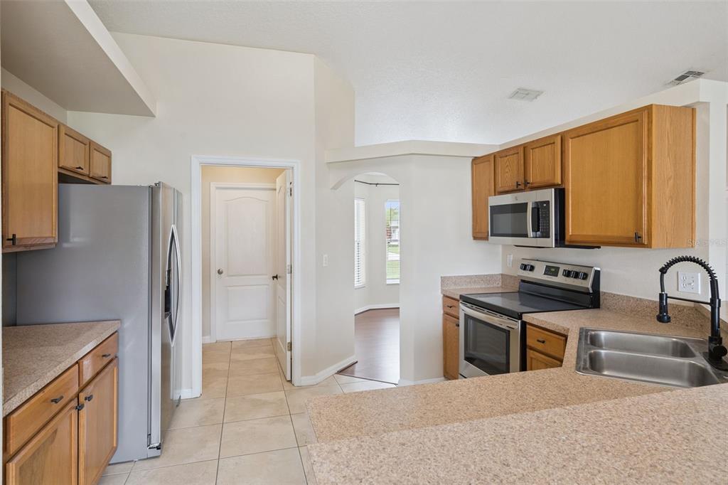 A kitchen with light wood cabinets, stainless steel appliances, and a beige countertop — 11434 PATRICO LOOP, CLERMONT, FL