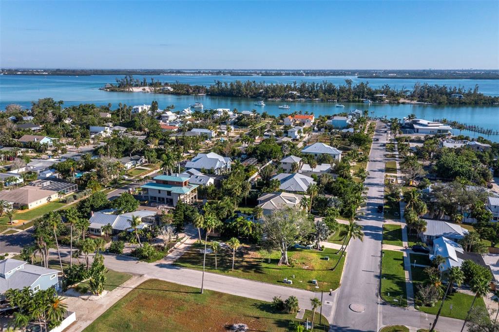 An aerial view shows a residential neighborhood with houses, palm trees, and a nearby waterway — 641 BROADWAY STREET, LONGBOAT KEY, FL