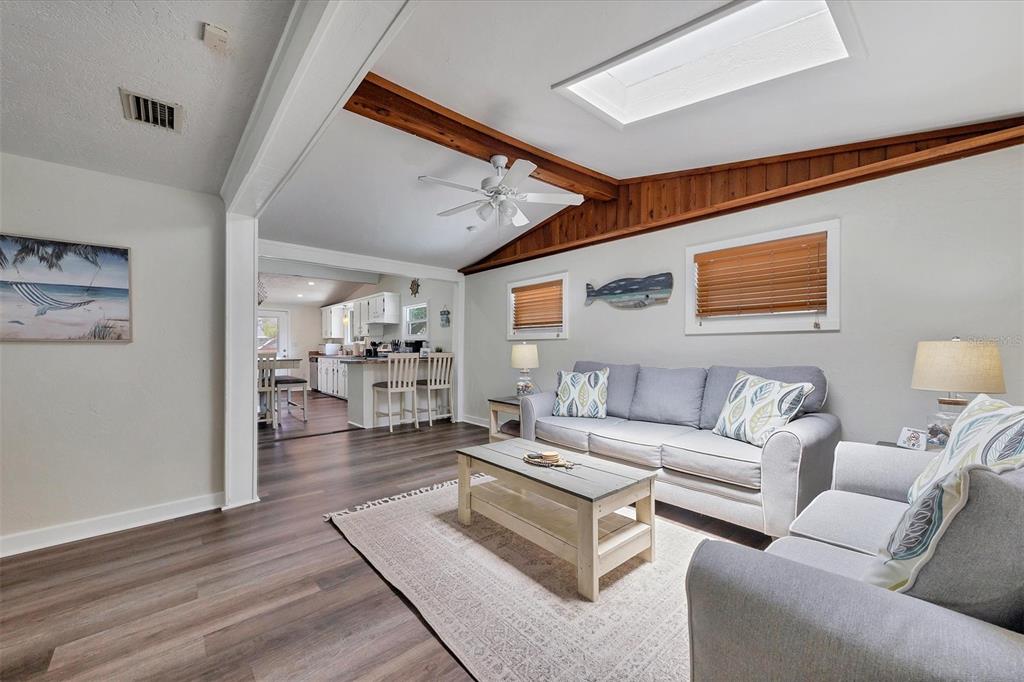 A living room with wood-look flooring, a vaulted ceiling with beams, and a skylight — 900 BEVERLY AVENUE, LARGO, FL
