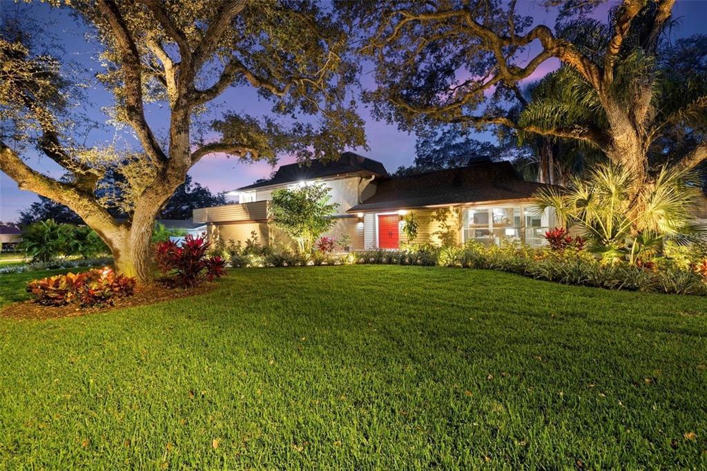 A swimming pool with a pink flamingo float sits in front of a two-story house — 1584 OAK LANE, CLEARWATER, FL
