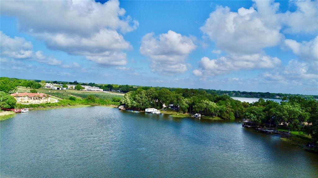 An aerial view shows a lake with several small houses along the wooded shoreline — 404 E ORLANDO AVENUE UNIT 8B, OCOEE, FL