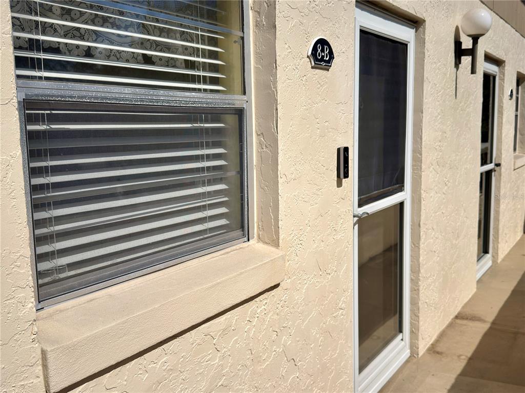 An exterior view of a stucco building featuring a window with blinds and a door — 404 E ORLANDO AVENUE UNIT 8B, OCOEE, FL