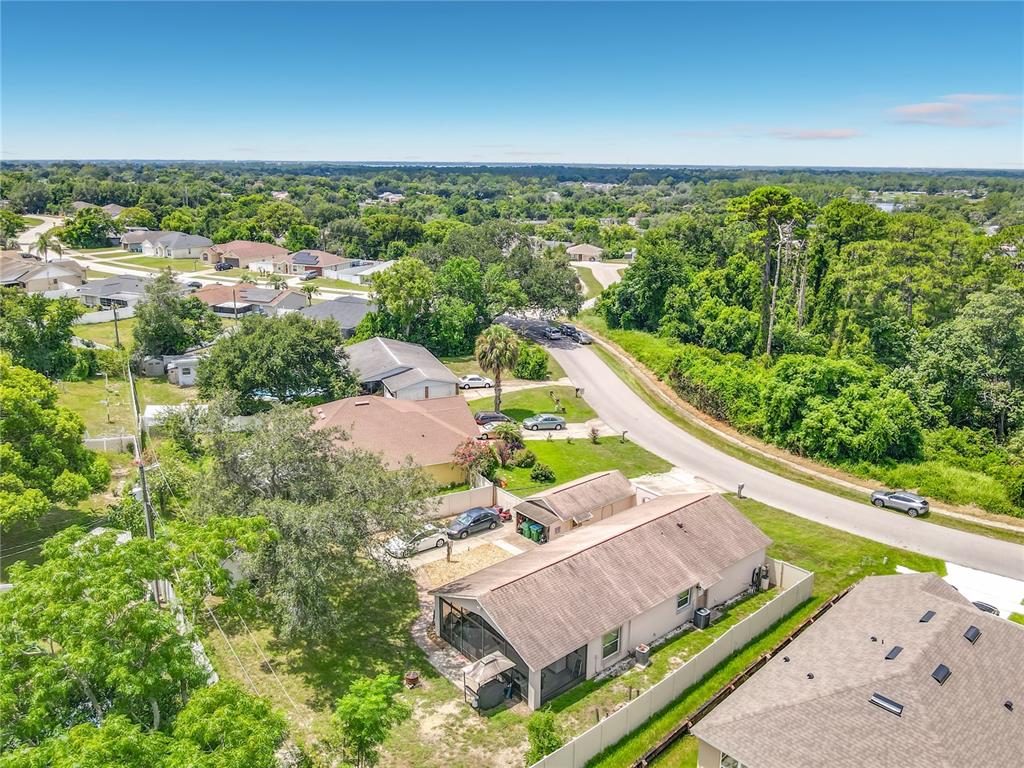A kitchen features wood cabinets, white appliances, a tiled backsplash, and a breakfast bar — 1123 W HANCOCK DRIVE, DELTONA, FL