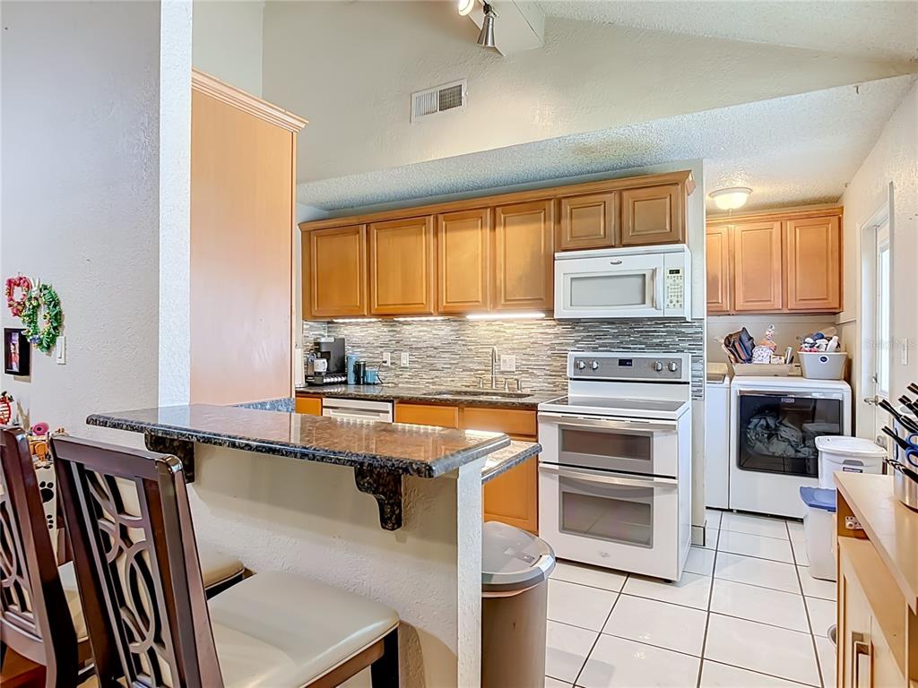 A dining area features a round wood-slice table against a large, vaulted brick wall — 1123 W HANCOCK DRIVE, DELTONA, FL