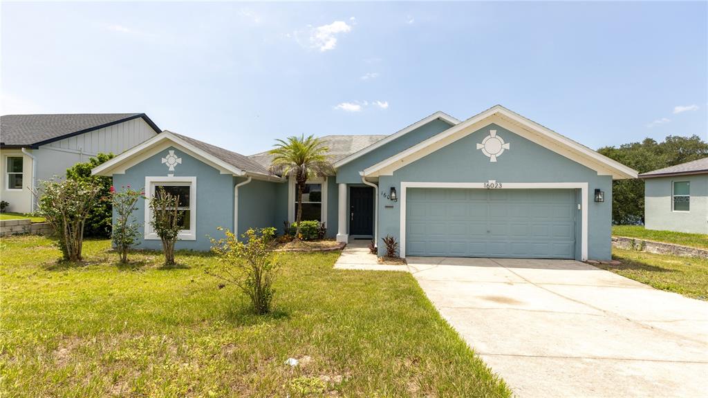 A light blue single-story house features a two-car garage and a front walkway — 16023 WORTHINGTON, MASCOTTE, FL
