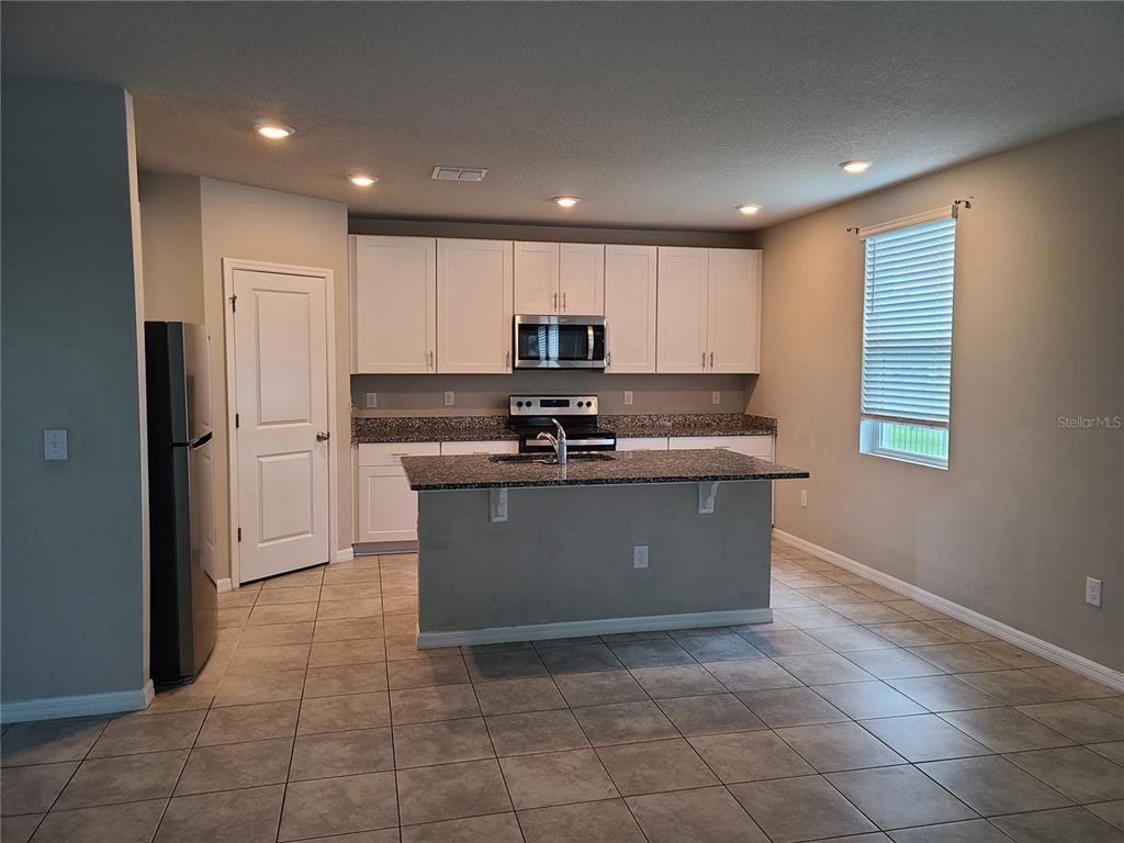 A room with light-colored tile flooring features a sliding glass door overlooking a pond — 10217 DAYBREAK GLEN, PARRISH, FL