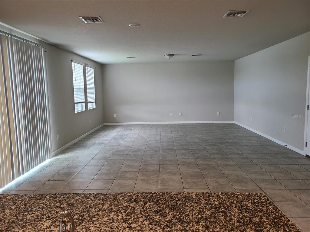 An entryway with gray tile flooring leads to a white front door and hallway — 10217 DAYBREAK GLEN, PARRISH, FL