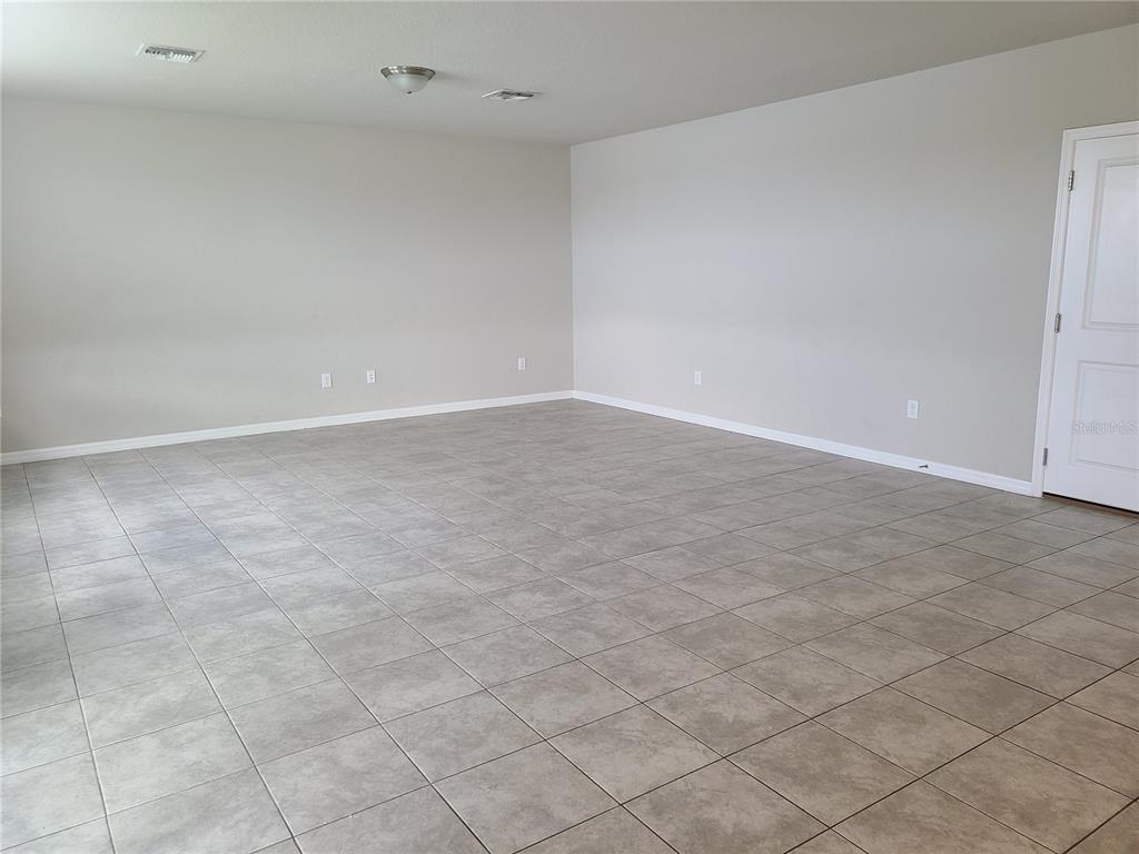 An empty room features light-colored walls, a single window with blinds, and tiled flooring — 10217 DAYBREAK GLEN, PARRISH, FL