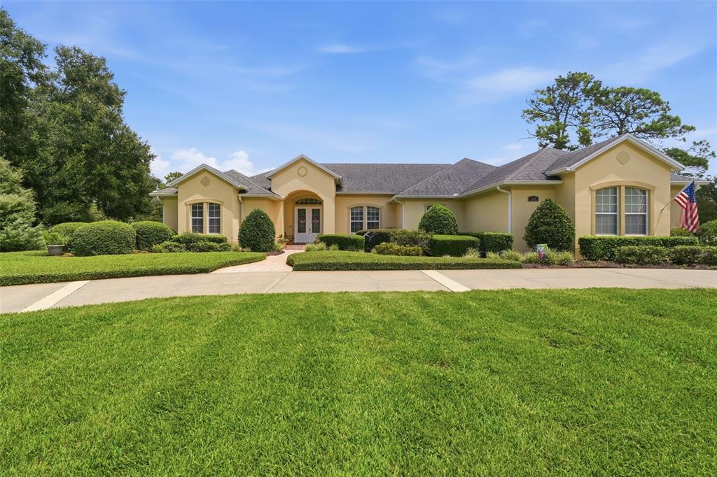 A single-story yellow house with a gray roof sits behind a large green lawn — 1681 TIMBER EDGE DRIVE, DELAND, FL