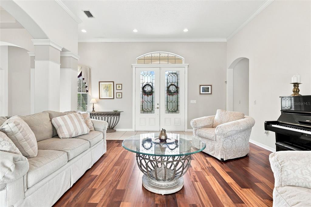 A living room features hardwood floors, a glass coffee table, a sofa, and a piano — 1681 TIMBER EDGE DRIVE, DELAND, FL