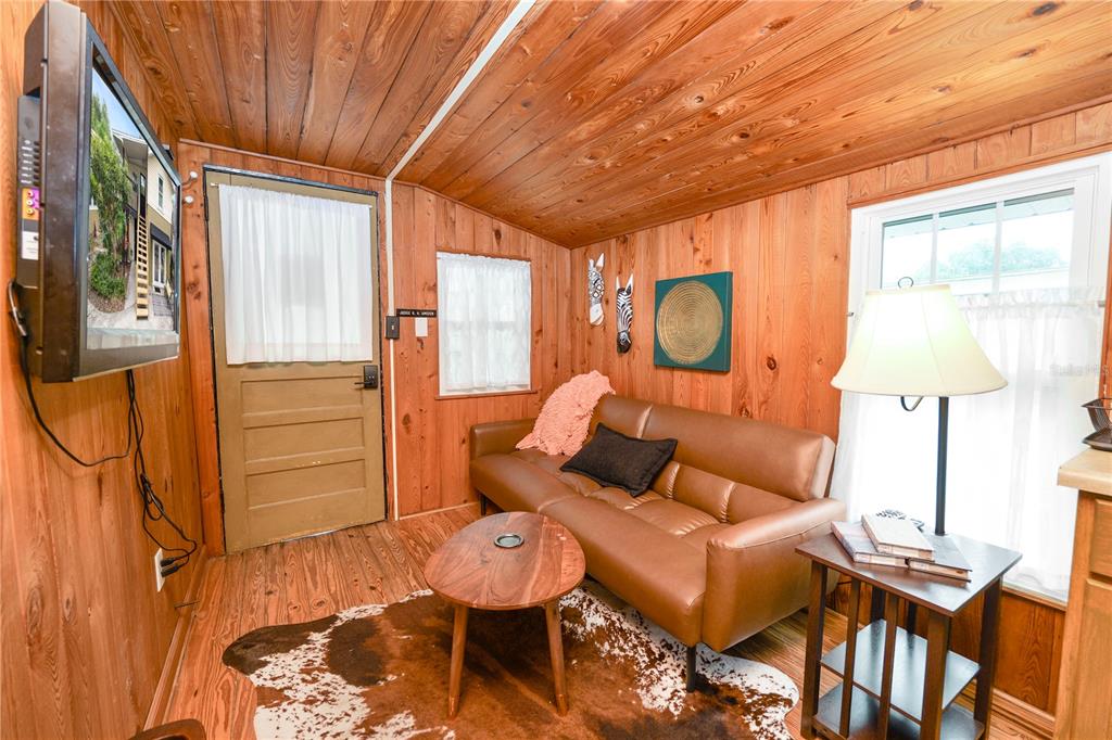 A small living room features wood-paneled walls, a brown sofa, a coffee table, and television — 1157 E EDGEWOOD DRIVE UNIT C, LAKELAND, FL