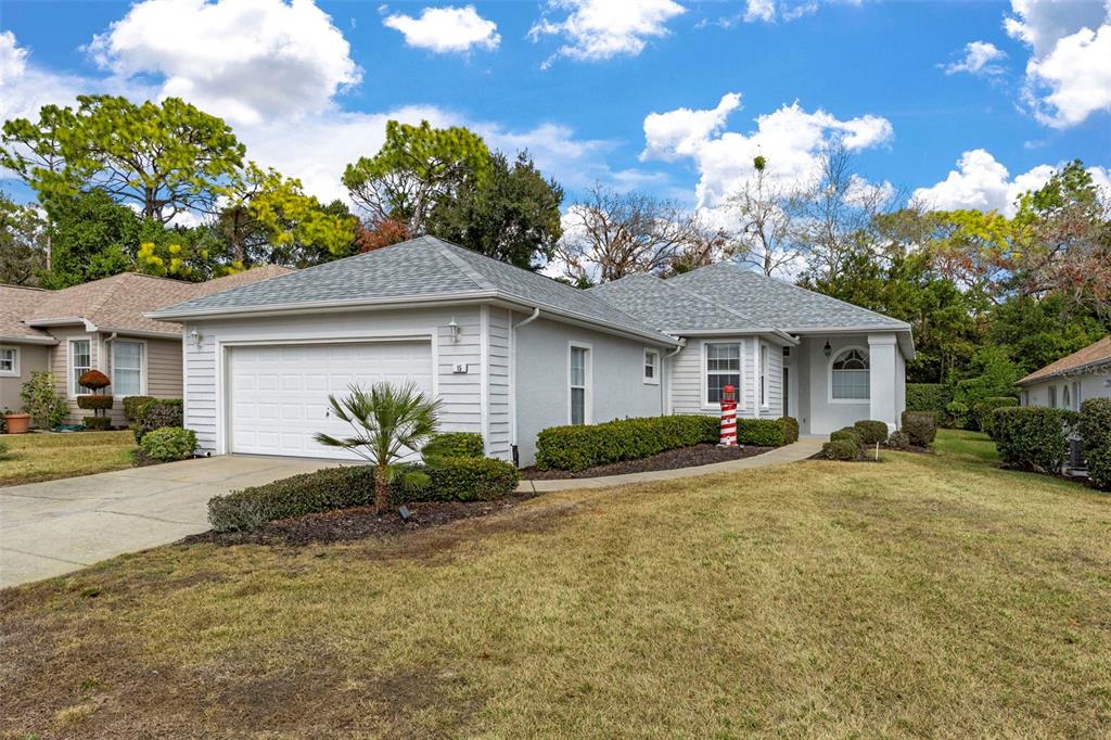 A light gray single-story house with a two-car garage and a landscaped front yard — 15 W BYRSONIMA LOOP, HOMOSASSA, FL