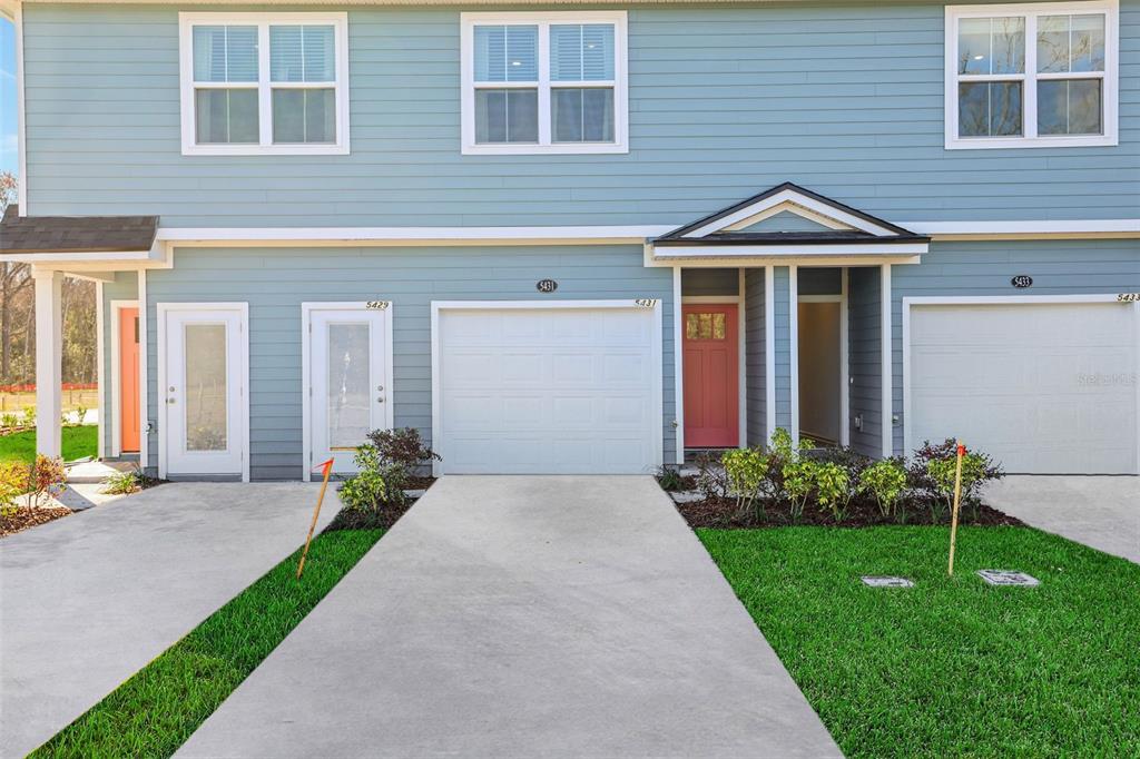 A multi-unit townhouse exterior features blue siding, white trim, concrete driveways, and a green lawn — 5522 ARROW LANE, JACKSONVILLE, FL