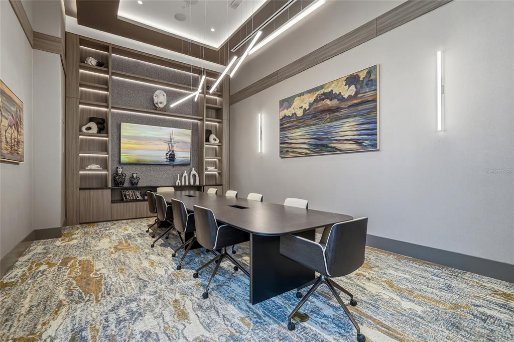 A modern conference room features a long table, chairs, built-in shelving, and abstract wall art — 275 1ST AVENUE S UNIT 1003, ST PETERSBURG, FL