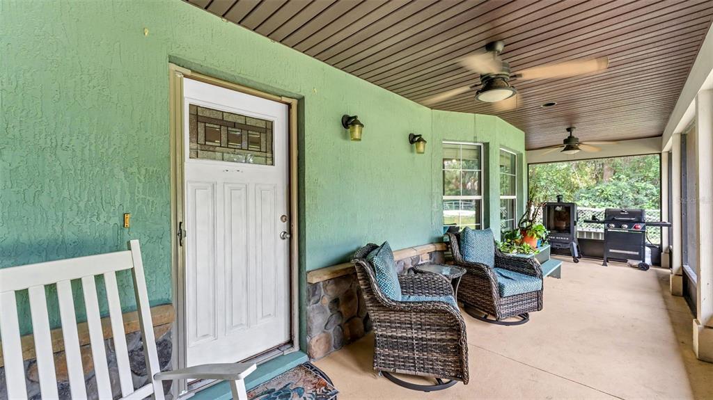 A covered porch features a white front door, wicker chairs, and two ceiling fans — 1002 W LAKE MARION ROAD, HAINES CITY, FL