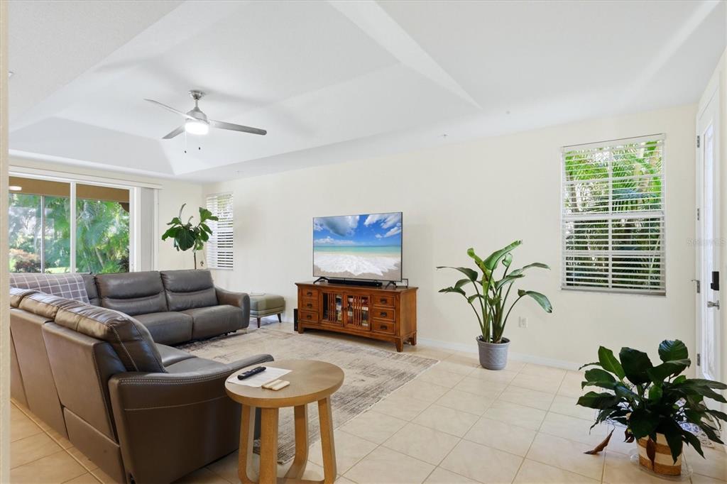A living room features a grey sectional sofa, a television on a wooden console, and plants — 3971 SQUARE EAST LANE UNIT 8, SARASOTA, FL