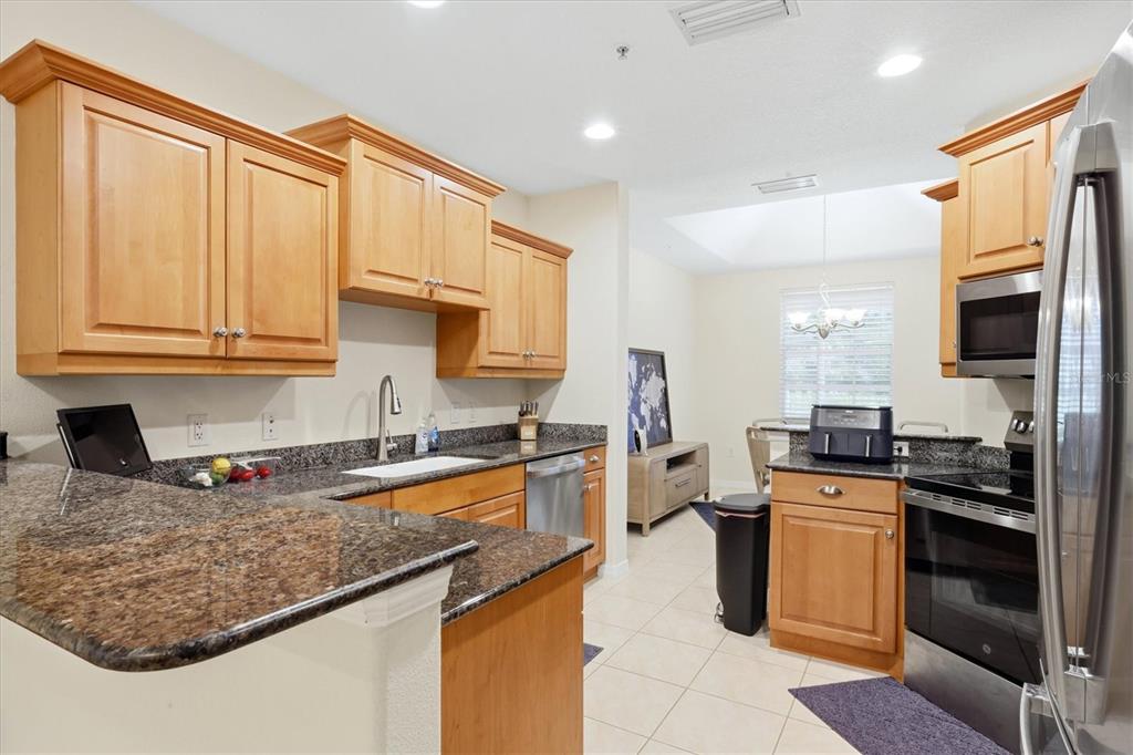 A kitchen with light wood cabinets, dark granite countertops, and stainless steel appliances — 3971 SQUARE EAST LANE UNIT 8, SARASOTA, FL