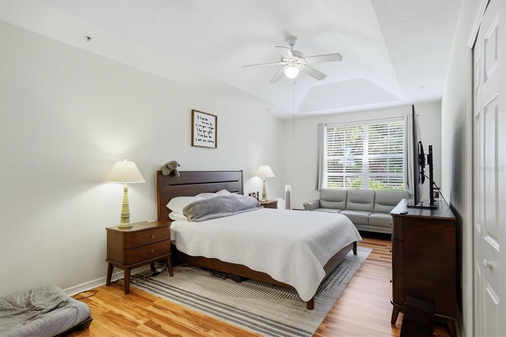 A bedroom features a queen bed, wooden furniture, a gray sofa, and a ceiling fan — 3971 SQUARE EAST LANE UNIT 8, SARASOTA, FL