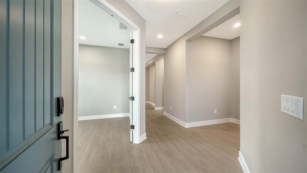 An entryway with light wood-look tile flooring leads to an open room and hallway — 345 POTENZA LOOP, NOKOMIS, FL