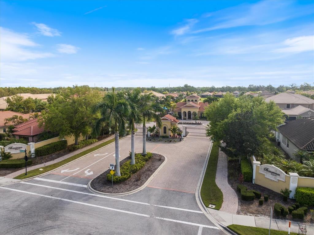 An aerial view of a gated community entrance with palm trees and a paved driveway — 6120 E 27 STREET E, ELLENTON, FL