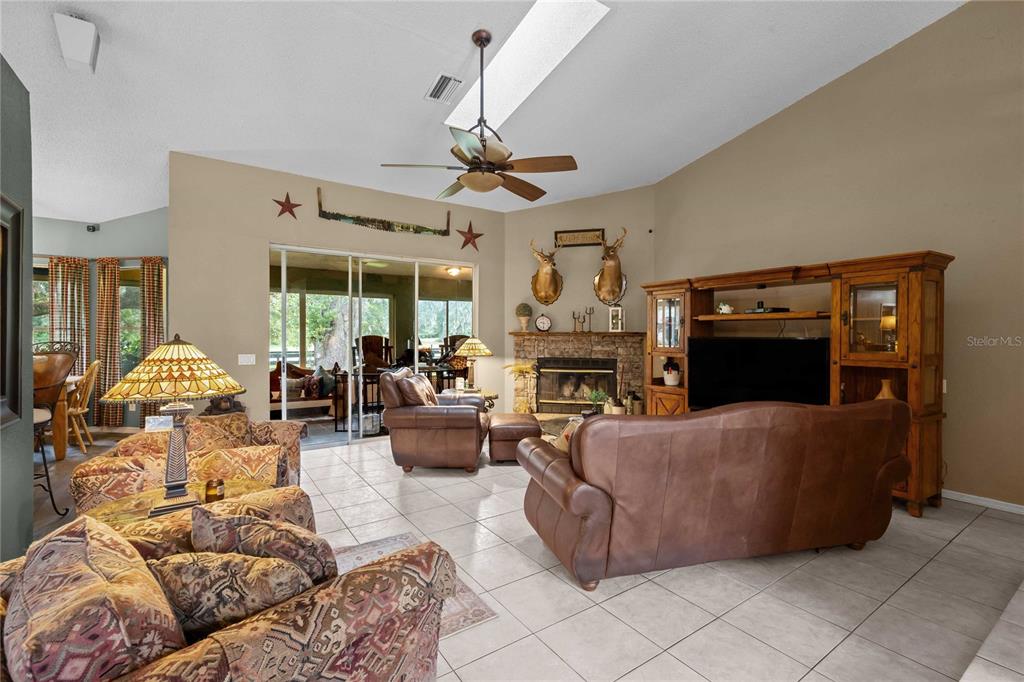 A living room features tile floors, a stone fireplace, leather furniture, and a vaulted ceiling — 4457 CR 542H, BUSHNELL, FL