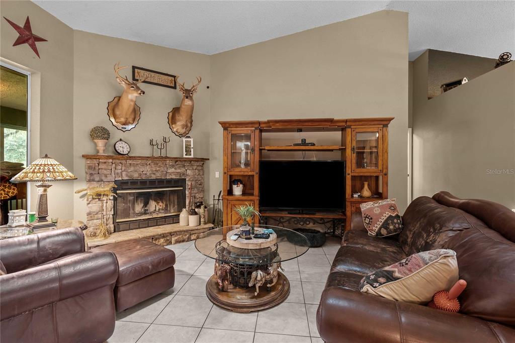 A living room features a stone fireplace, two deer mounts, and a large wooden entertainment center — 4457 CR 542H, BUSHNELL, FL
