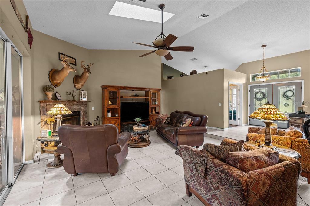 A living room features tile floors, a stone fireplace, leather furniture, and a vaulted ceiling — 4457 CR 542H, BUSHNELL, FL